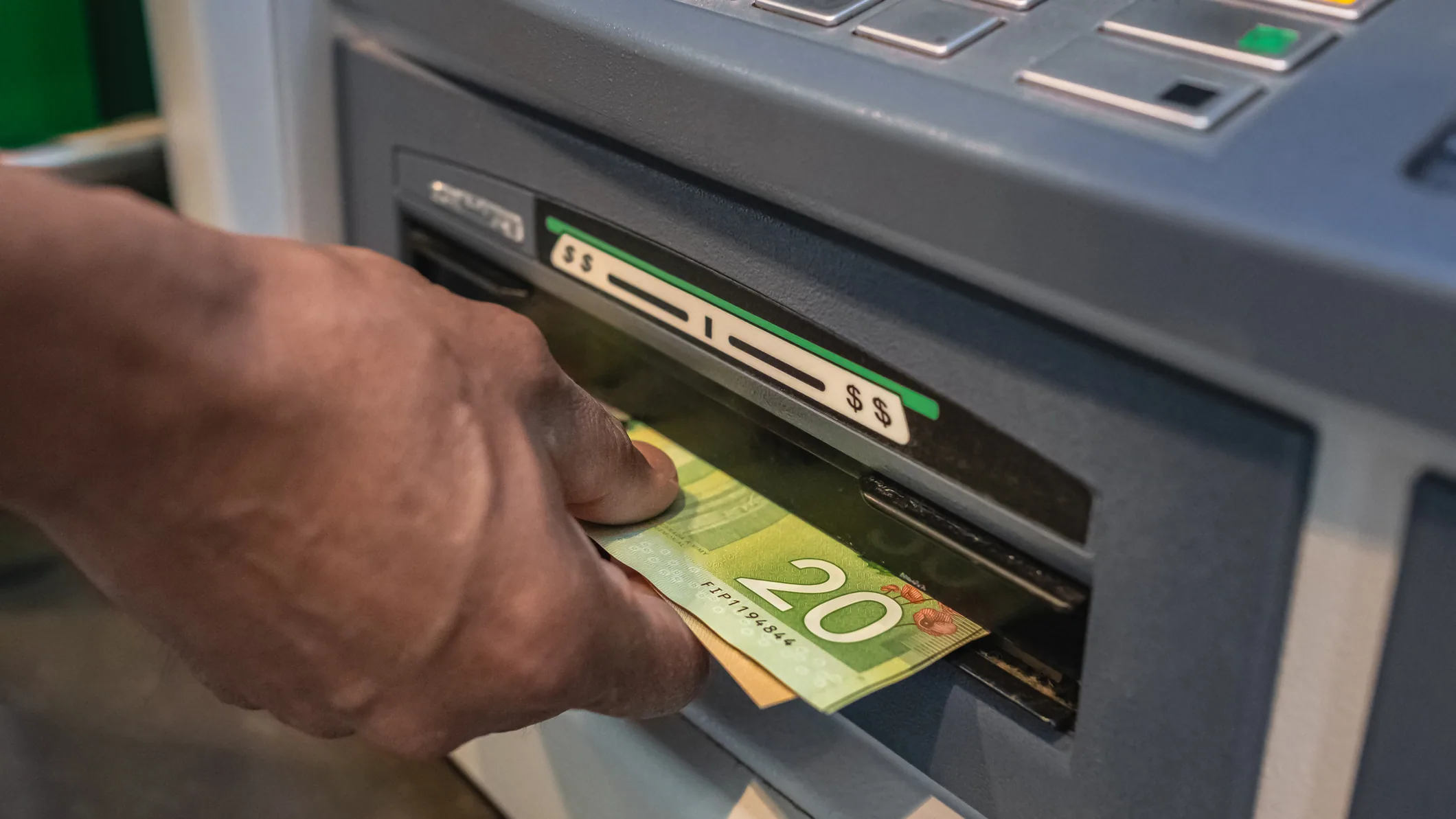 A man standing at a modern ATM machine inside a clean bank lobby